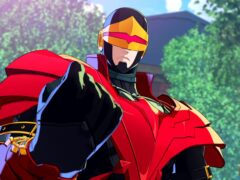 Phoenix Cyclops in a red and gold Phoenix costume with a gold visor, pointing toward the viewer in front of trees
