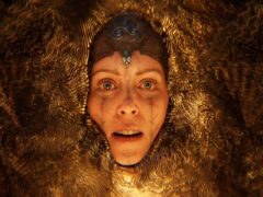 Close-up of Senua's face surrounded by golden, rippling textures in a still from the Senua reveal trailer