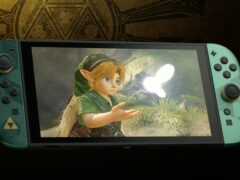 Zelda 40th Anniversary Edition Nintendo Switch 2 with green Joy-Con controllers and a Triforce emblem, showing young Link and a glowing fairy on screen